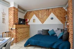 um quarto com uma cama azul e uma parede de tijolos em Les Herbages em Mers-les-Bains