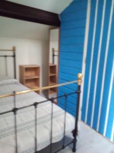 1 dormitorio con cama y pared azul en Pedro's garden, en Pontenx-les-Forges