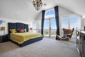 a bedroom with a bed and a chair and windows at Luxury & plush lifestyle 5 Bedroom house in Mt Eliza in Mount Eliza