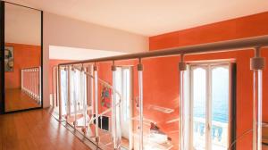 a room with orange walls and a staircase with windows at Terrazza Torno in Torno