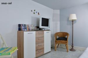 um quarto com uma cómoda, uma televisão e uma cadeira em Les Herbages em Mers-les-Bains