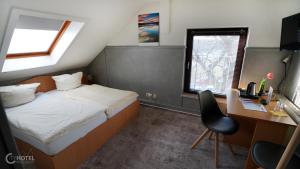 a small bedroom with a bed and a desk and a chair at Cityhotel Magdeburg in Magdeburg