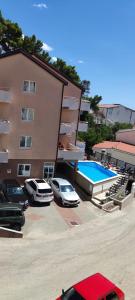 a building with cars parked next to a swimming pool at Apartments Vila Adrijana & Fitness Studio WOLF BV in Baška Voda