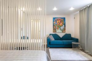 タリンにあるCozy Stylish Studio Apartment with FREE Parking by Centralapartmentsの青いソファと絵画が備わるベッドルーム1室