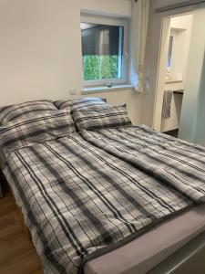 1 cama con manta a cuadros y ventana en Ferienwohnung Fenke 2.0, en Lindlar