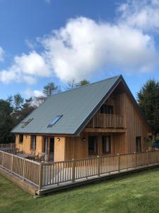 a large wooden cabin with a gambrel roof at Lord Galloway 36 with Hot Tub in Newton Stewart