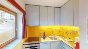 een gele keuken met een wastafel en een raam bij Apartment Piz Cotschen B in Pontresina