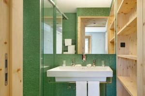 a bathroom with a white sink and green tiles at Alpine Lodge 2-Bett-Wohnung Chesa Plattner "Bergbahnen All inklusiv" im Sommer in Pontresina