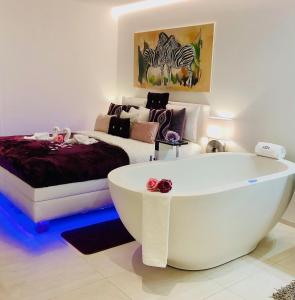 een wit bad in een kamer met een bed bij perfect lifestyle Design Boutique & Private SPA in Gebenstorf