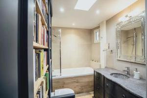 a bathroom with a sink and a bath tub and a book shelf at Quartiers Enfants Rouges,Bretagne - Appartement d'architecte 4P in Paris
