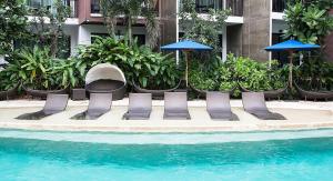 a group of chairs and umbrellas next to a pool at Centara Life Maris Resort Jomtien in Jomtien Beach