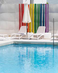 una piscina con sedie e ombrelloni di The Purple Hotel - Adults Only a San Antonio