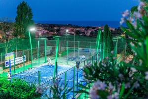 um campo de ténis com pessoas a jogar nele à noite em !!! PADEL - PISCINA - CALCIO !!! - Aparthotel Isabella em Sciacca