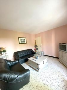 a living room with a black leather couch and a coffee table at Location chaleureuse à Orgnac-l'Aven avec piscine partagée in Orgnac-lʼAven
