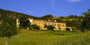 an old brick building in a field of grass at La Ferme de la Condamine in Saint-André-de-Rosans