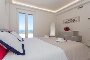 Dormitorio blanco con cama grande y vistas al océano en Villa Annalisa by PosarelliVillas, en Pizzolungo