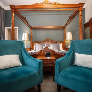 a bedroom with a bed and two blue chairs at Caistor Hall in Norwich