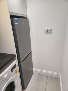 a kitchen with a refrigerator and a washing machine at Fancy Basement Flat B in London