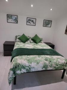 a bedroom with a bed with a green and white comforter at Fancy Basement Flat B in London