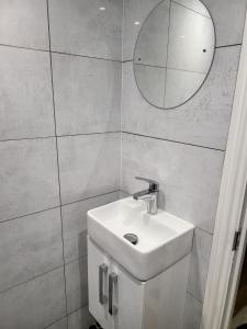a bathroom with a white sink and a mirror at Fancy Basement Flat B in London