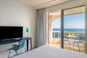a bedroom with a bed and a television and a balcony at Hôtel Riva Art & Spa in Menton