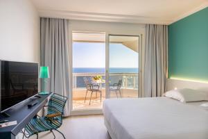 a bedroom with a bed and a television and a balcony at Hôtel Riva Art & Spa in Menton