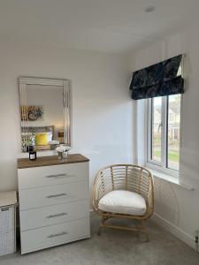 um quarto com uma cómoda, uma cadeira e um espelho em Hope House em Swindon