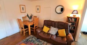ein Wohnzimmer mit einem Ledersofa und einem Tisch in der Unterkunft Greenbrae East in Crieff