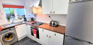 cocina con armarios blancos y nevera de acero inoxidable en Greenbrae East en Crieff