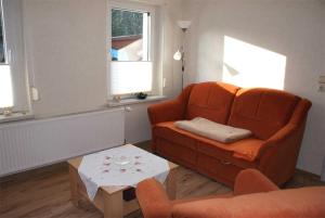 salon z pomarańczową kanapą i stołem w obiekcie Ferienwohnung Patzig RUeG 2131 w mieście Patzig