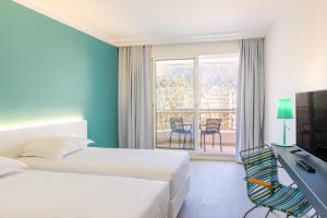 a hotel room with two beds and a desk and a balcony at Hôtel Riva Art & Spa in Menton