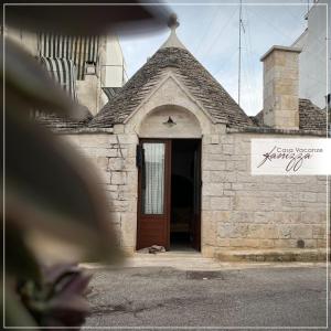 - un petit bâtiment en pierre avec une porte marron dans l'établissement Trullo Cometa, à Alberobello