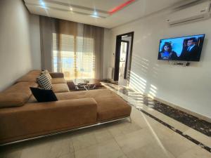 a living room with a couch and a flat screen tv at Accueillant S+1 jardin de carthage in Tunis