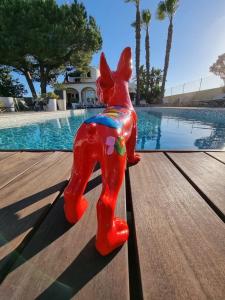 uma estátua de um cão vermelho sentado numa mesa perto de uma piscina em Casa Bela Moura, Boutique Hotel & Wine em Porches