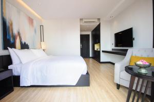 een slaapkamer met een wit bed en een bank bij GLOW PARK HOTEL Grand Royal Palace in Phnom Penh