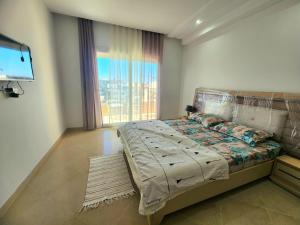 a bedroom with a bed and a large window at Accueillant S+1 jardin de carthage in Tunis
