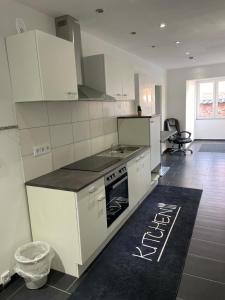 a kitchen with white cabinets and a black counter top at Appartment am Rosenplatz in Brechtorf