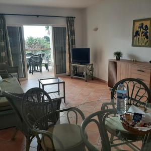 sala de estar con mesa, sillas y TV en Clube Alvor Ria - Waterfront luxury apartments with stunning views, en Alvor