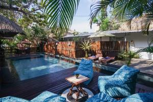 a villa with a swimming pool and a woman sitting on a patio at Kampung 168 in Jimbaran
