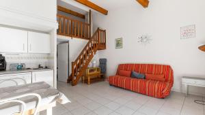 a living room with a red couch and a staircase at Perles du Soleil- 50- Maison mezzanine- 6 pers in Cap d'Agde