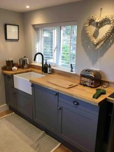 a kitchen with a sink and a heart hanging on the wall at Cute studio cottage. Wood burner. Amazing views in Longhope