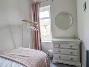 a bedroom with a bed and a mirror and a dresser at 15 Clitheroe in Skipton