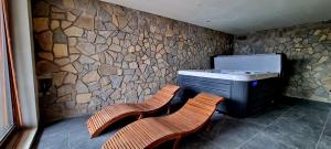 two chairs and a desk in a room with a stone wall at Chalet Liptov Izipovce in Ižipovce