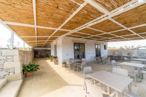 un patio con tavoli, sedie e soffitto in legno di Sarmenti Agriresort a Otranto