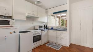 biała kuchnia z białymi urządzeniami i oknem w obiekcie Sun Village- 39- Maison duplex- 6 pers w Cap d'Agde