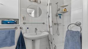 W łazience znajduje się umywalka oraz prysznic z niebieskimi ręcznikami. w obiekcie Sun Village- 39- Maison duplex- 6 pers w Cap d'Agde
