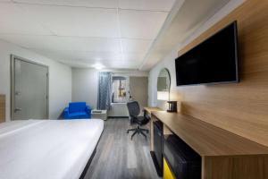 a hotel room with a bed and a flat screen tv at Days Inn by Wyndham Fredericksburg North in Fredericksburg
