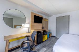 a hotel room with a desk and a bed and a mirror at Days Inn by Wyndham Fredericksburg North in Fredericksburg