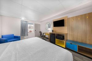 a hotel room with a bed and a desk and a tv at Days Inn by Wyndham Fredericksburg North in Fredericksburg