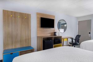 a hotel room with a bed and a desk and a tv at Days Inn by Wyndham Fredericksburg North in Fredericksburg
